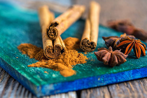 Ceylon cinnamon (sticks and powder) and star anise on a wooden board.